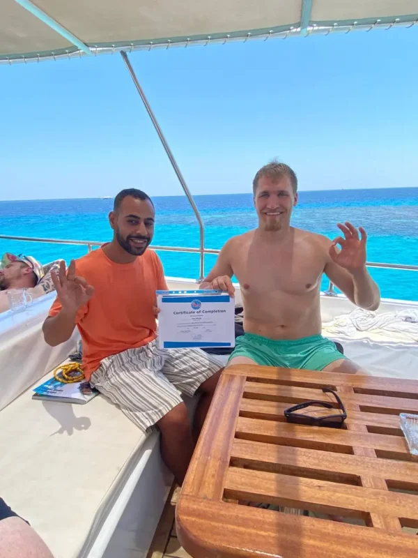 PADI Open Water Diver student and instructor Youssef celebrating certification on a boat in Hurghada
