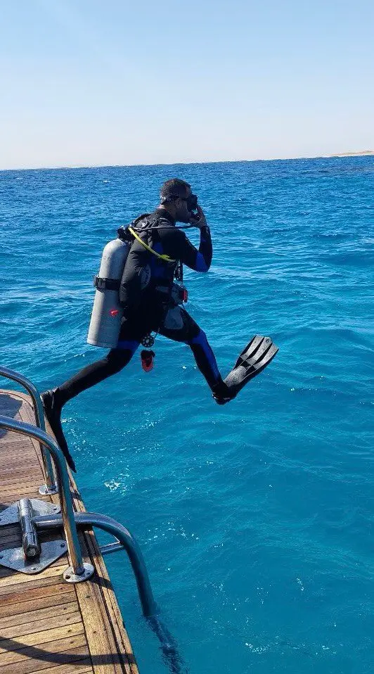 Professional diver showing the correct giant stride entry technique from a boat in the Red Sea